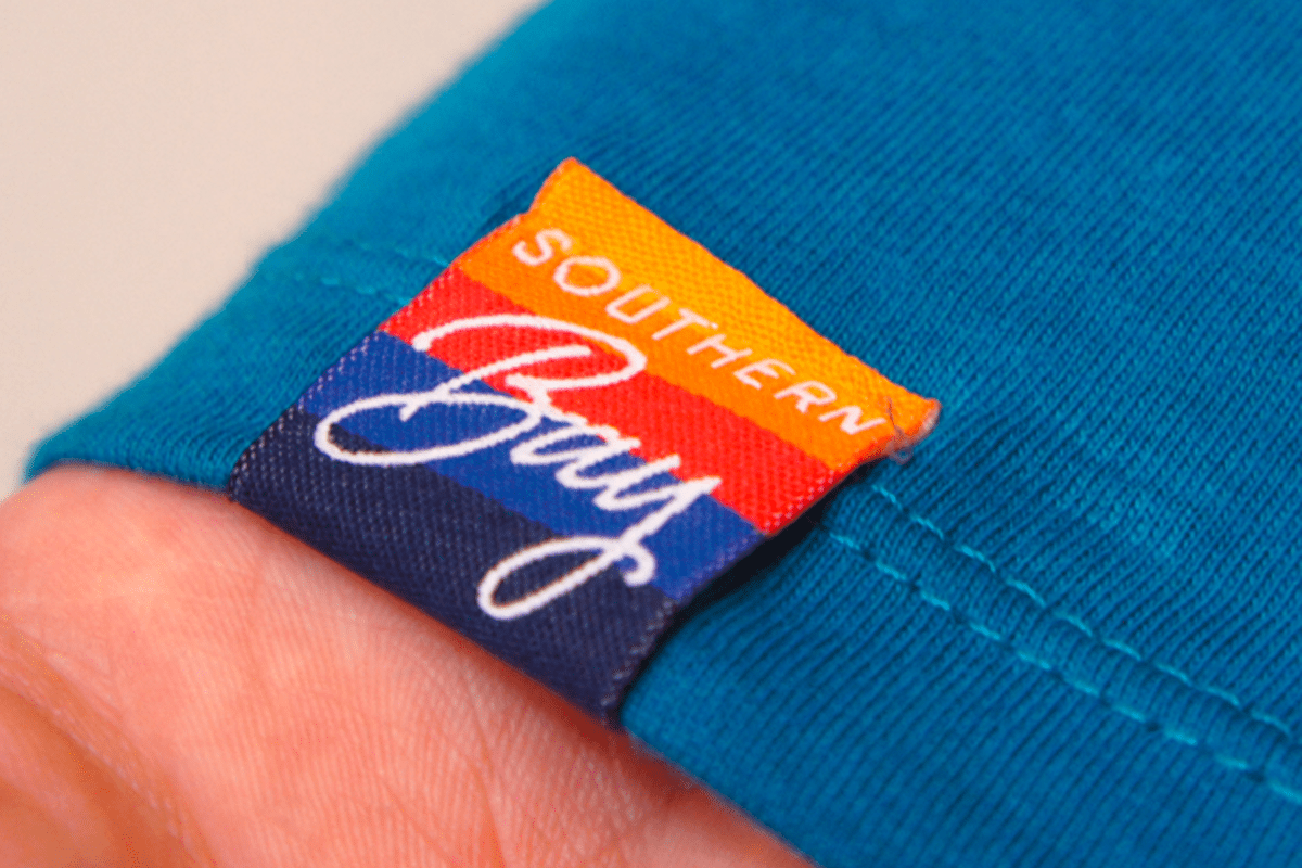 Close-up of a meticulously sewn woven hem tag on the sleeve of a garment, showcasing teeone's attention to detail and quality finishing services.