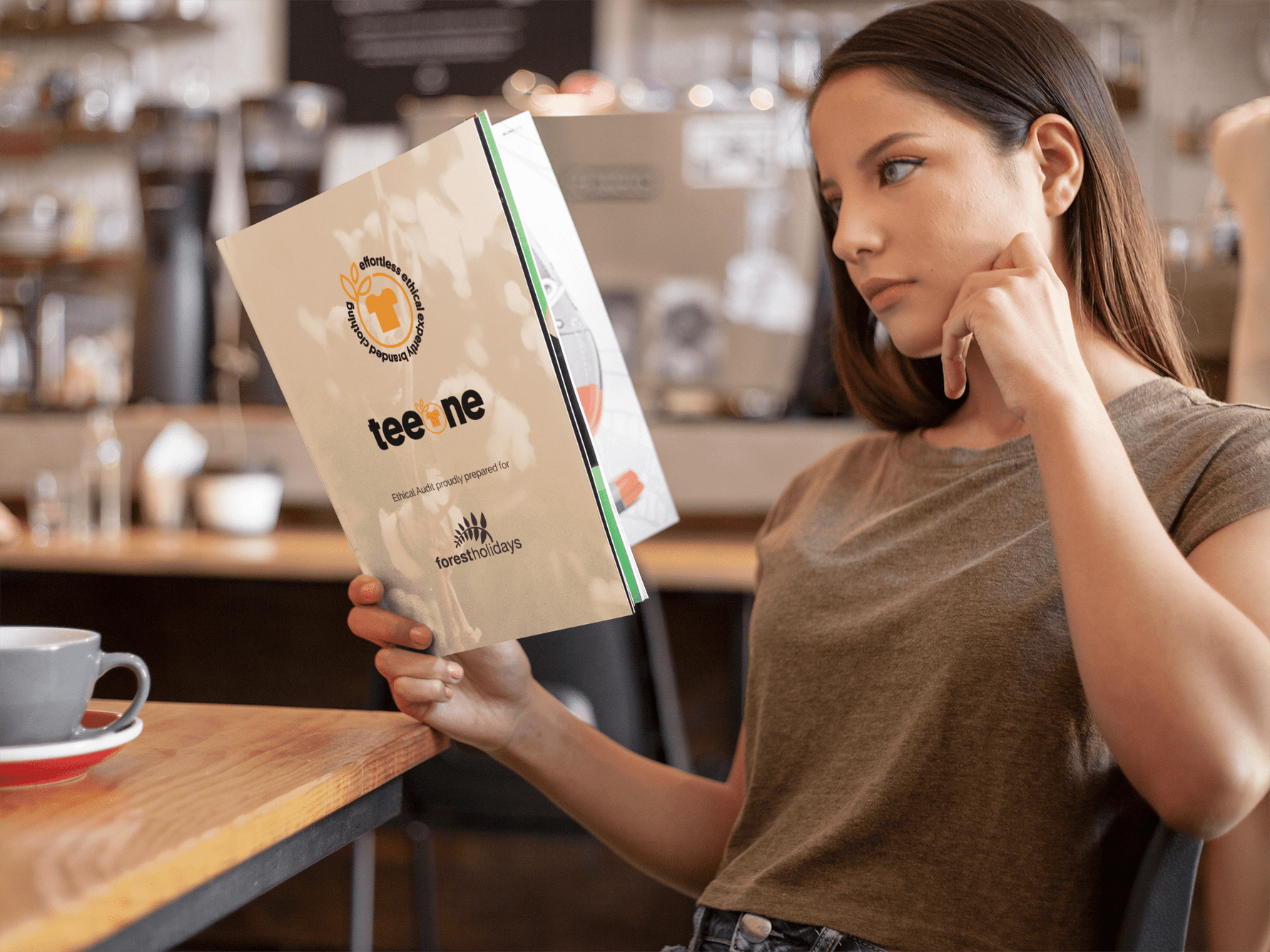 Woman engrossed in reading her printed Teeone sustainability audit report, understanding the ethical practices of her business, while in a coffee shop.