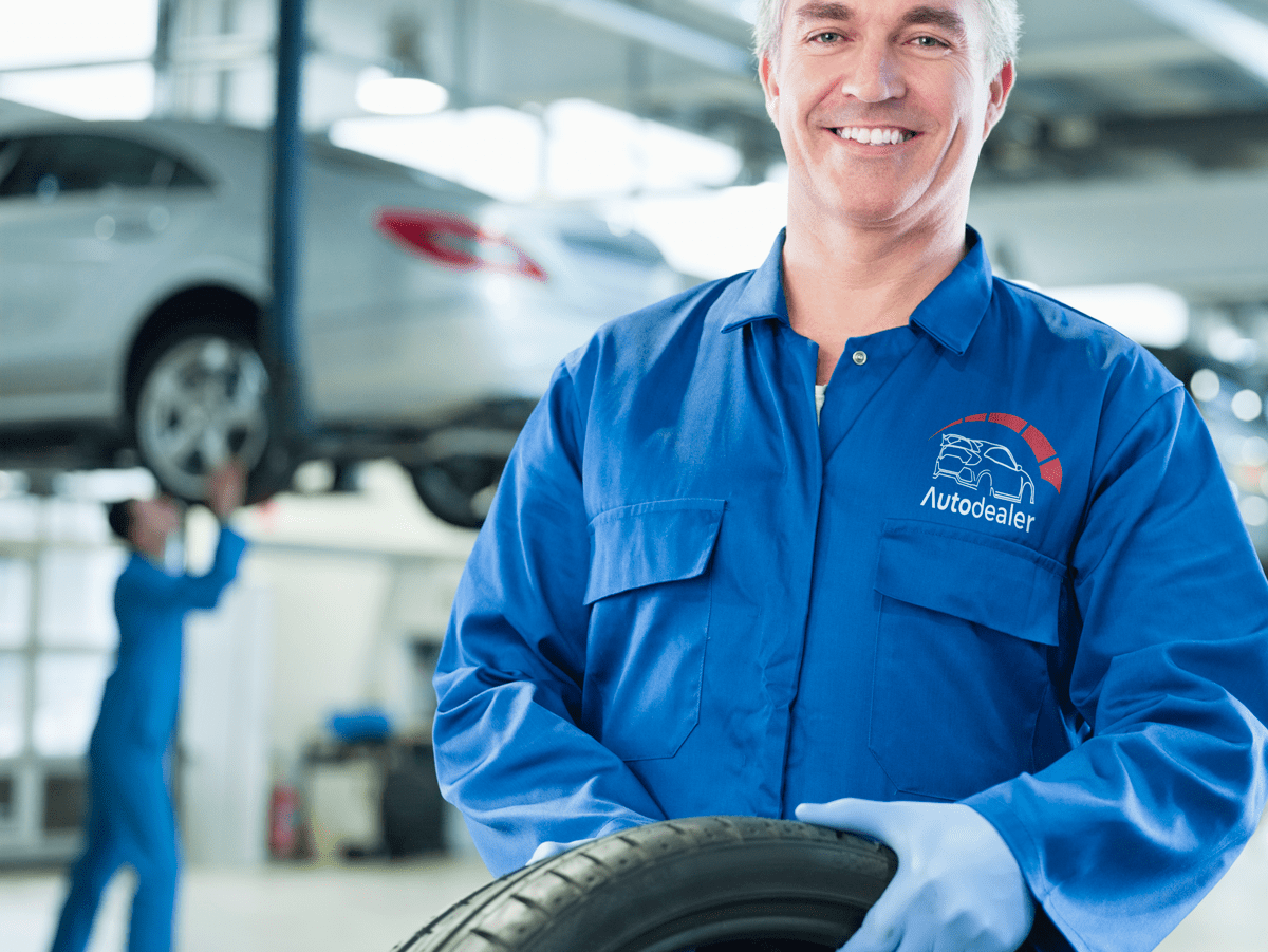 A professional mechanic in a clean garage, wearing an overall emblazoned with his company's brand, printed by teeone. This overall showcases our superior print quality and attention to detail, perfect for workwear applications